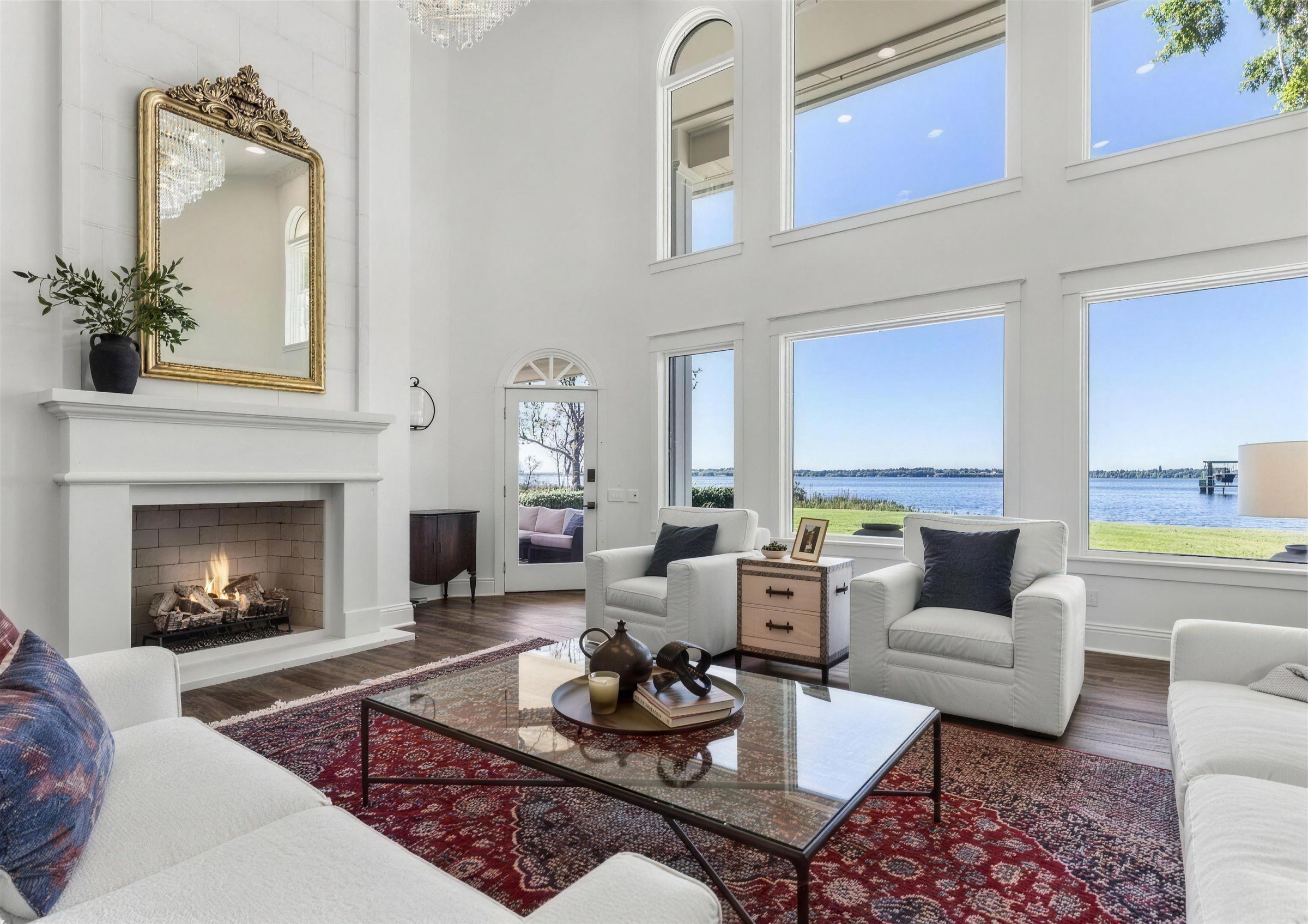 Bright living room in a custom Jacksonville home after interior painting, white walls and trim, a white fireplace and a view of the water