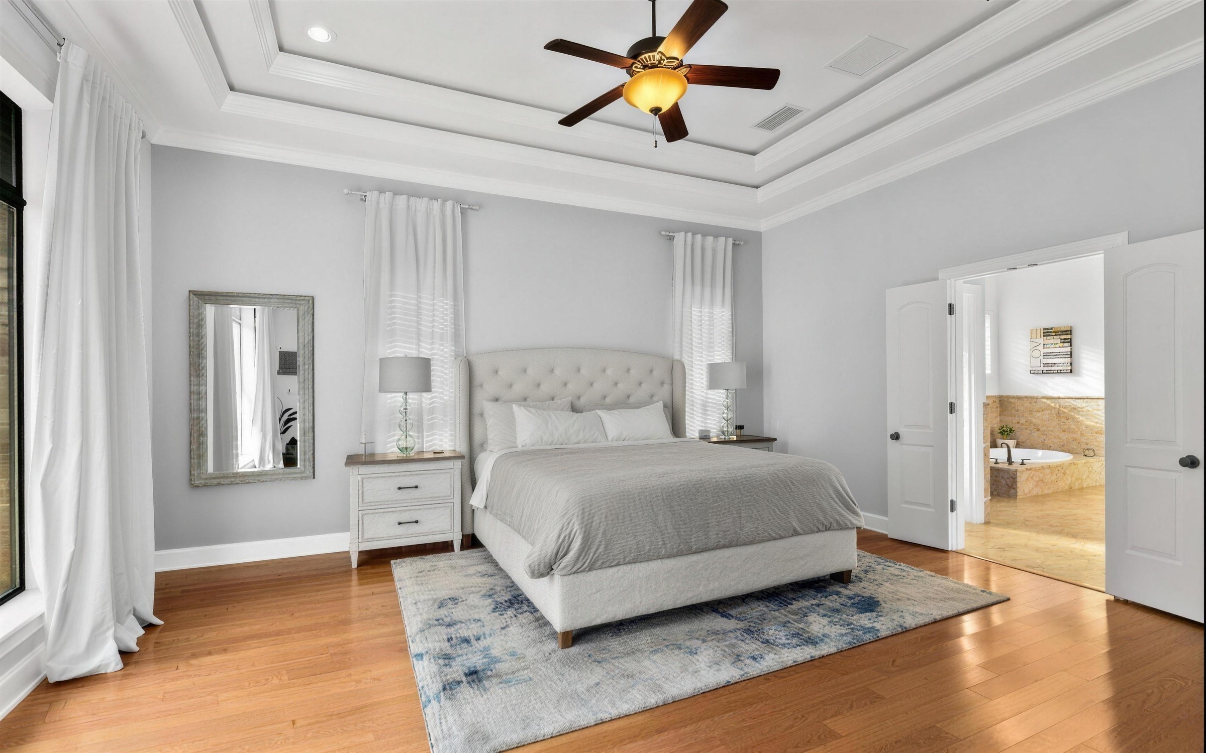Primary suite after interior painting, soft grey walls, white trim and a tray ceiling