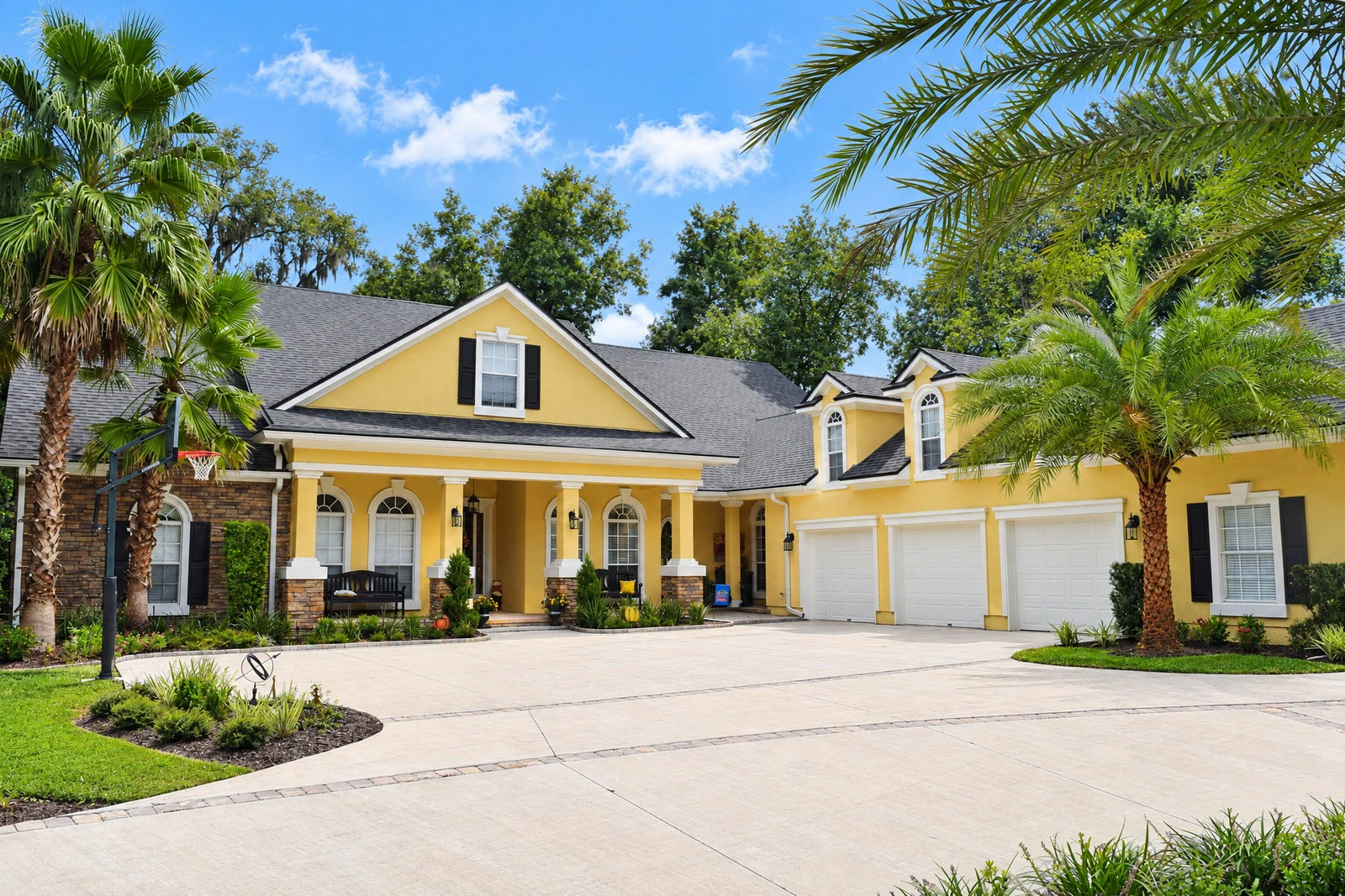 Yellow exterior with black shutters and three-car garage after repaint