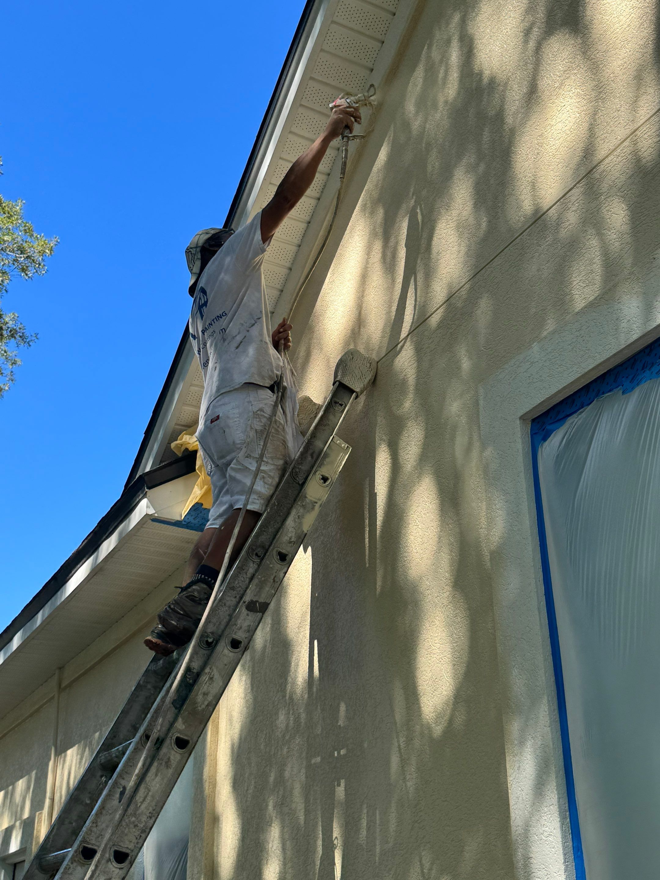 Crew applying exterior coatings to a synthetic stucco home in Queen’s Harbour