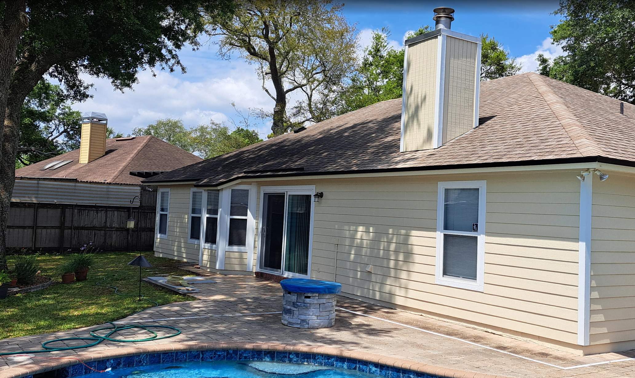 Back of an East Arlington home in Jacksonville FL after exterior painting, pale yellow siding and white trim by the pool