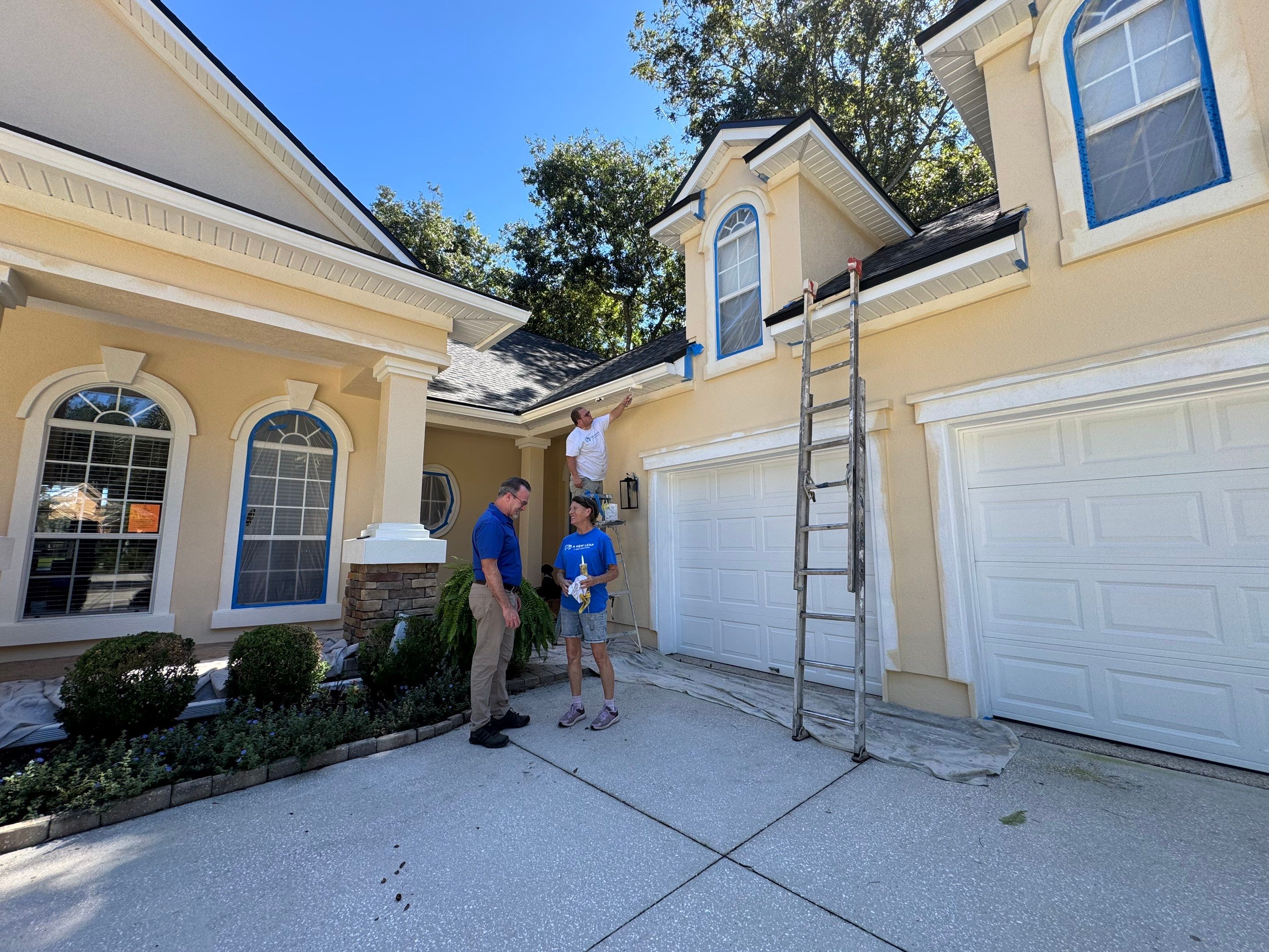 Professional painters completing exterior prep on a synthetic stucco home in Queen’s Harbour