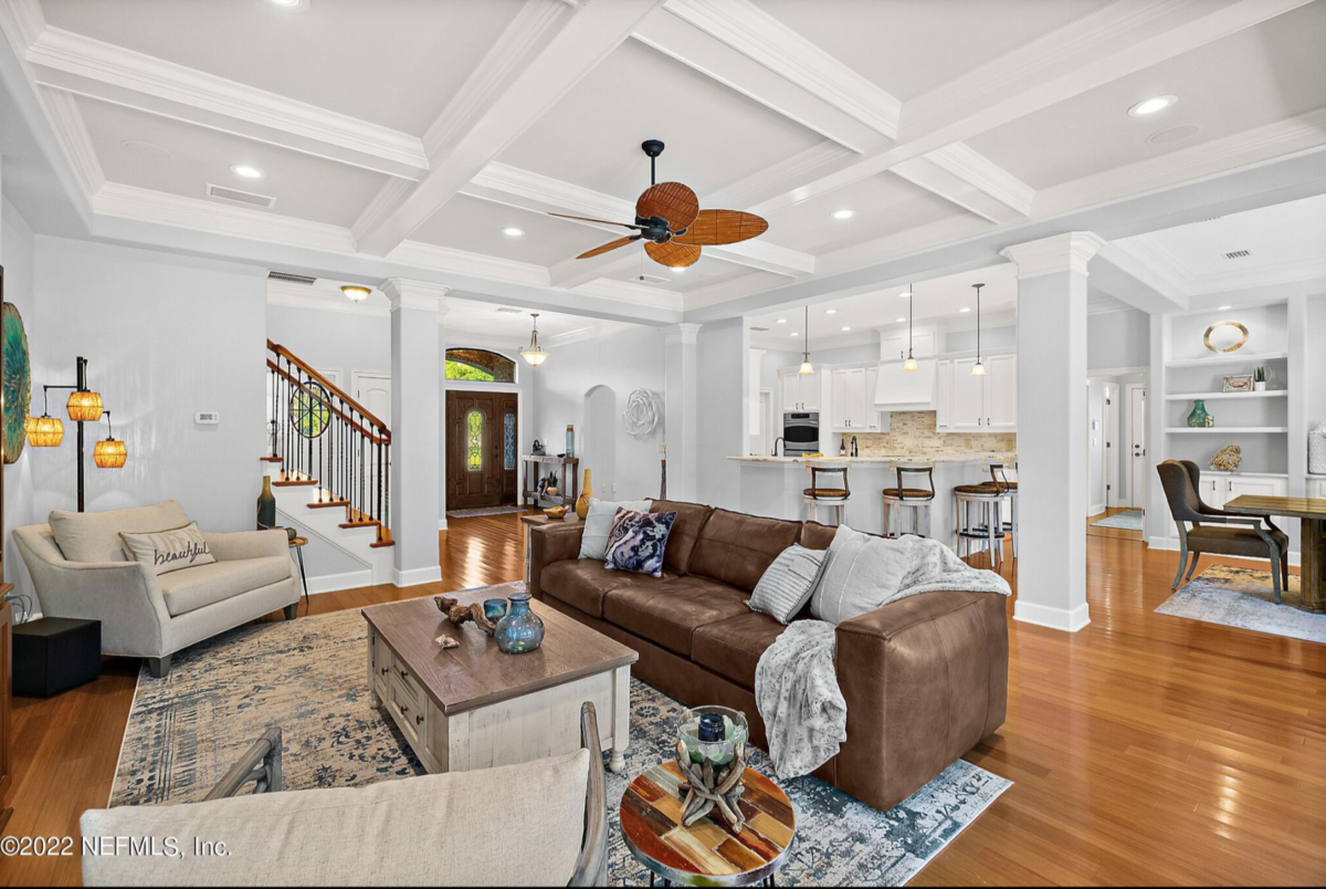 Open concept living room with fresh interior painting in Jacksonville FL featuring light gray walls, white trim, and coffered ceilings Title: Open Concept Living Room Interior Painting — Jacksonville, FL