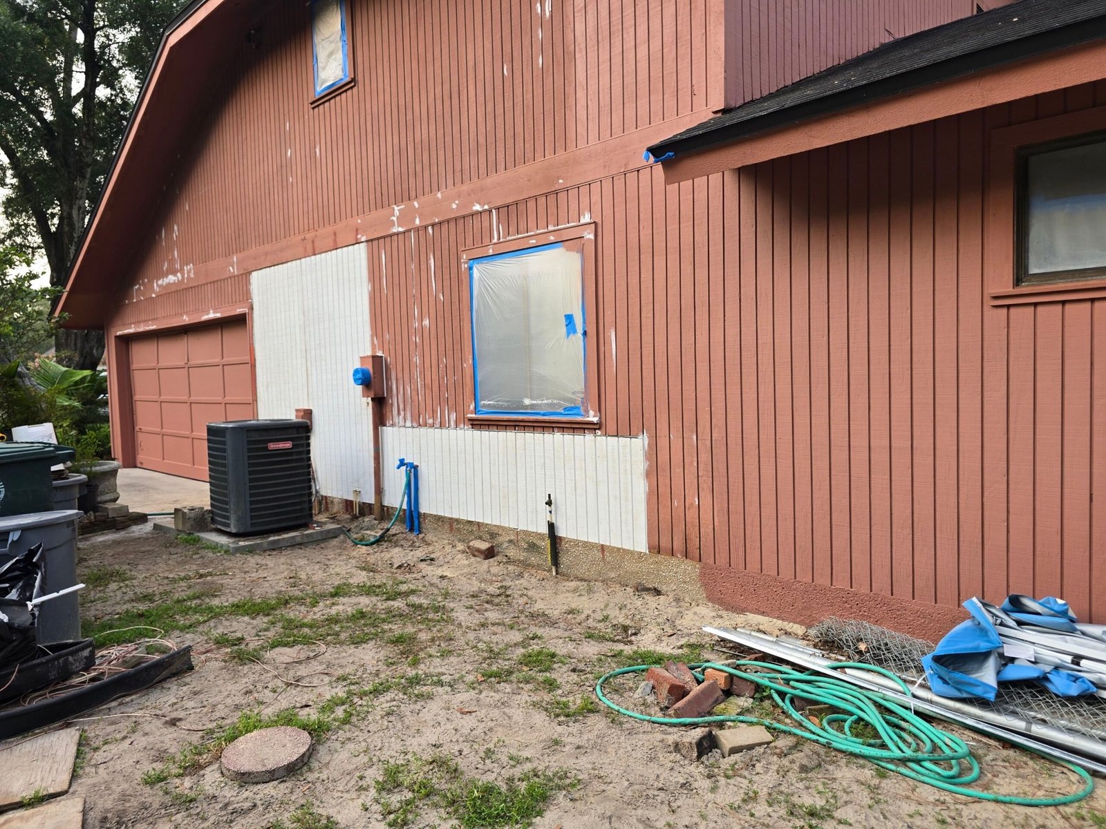 Completed T1-11 Repairs Ready for Painting — Secret Cove Jacksonville Completed T1-11 siding repairs on Secret Cove Jacksonville home — new replacement panels installed from ground level to mid-wall, adjacent existing siding visible above, surface ready for exterior painting
